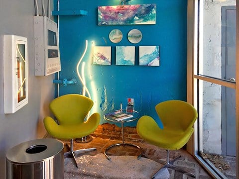 a living room with green chairs and a blue wall