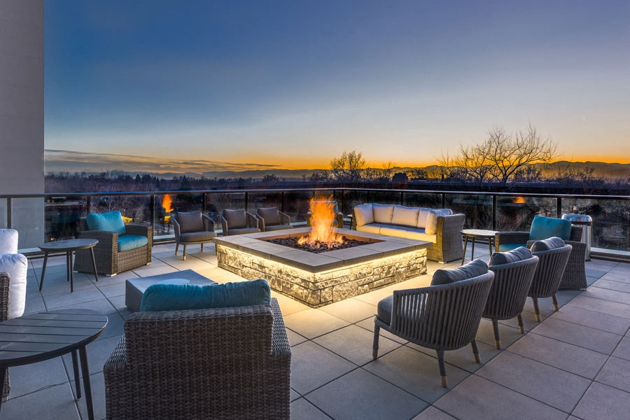 a patio with a fire pit and chairs on a rooftop