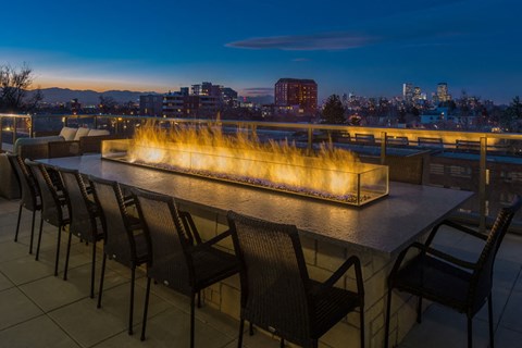 a rooftop fire pit at night with a city in the background