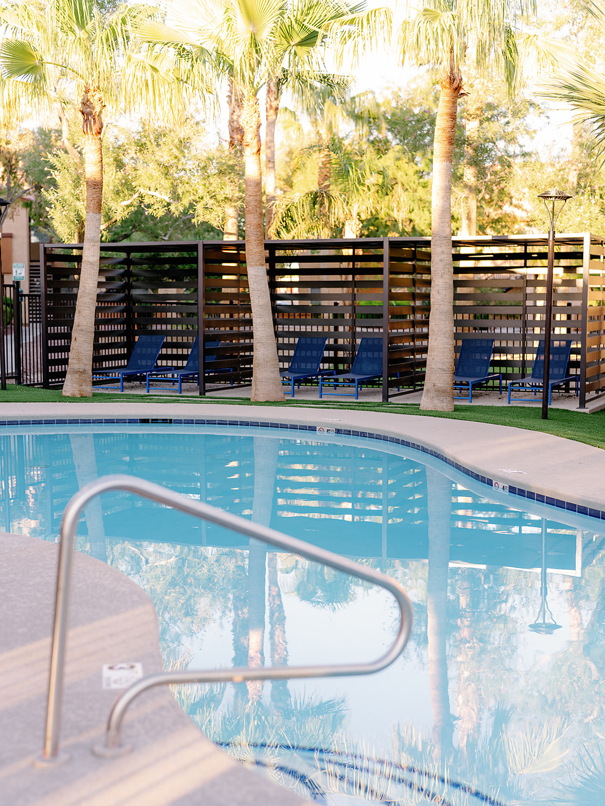 a swimming pool with chairs and palm trees