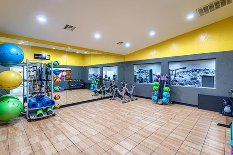 a gym with a bunch of exercise equipment on the floor and a yellow wall