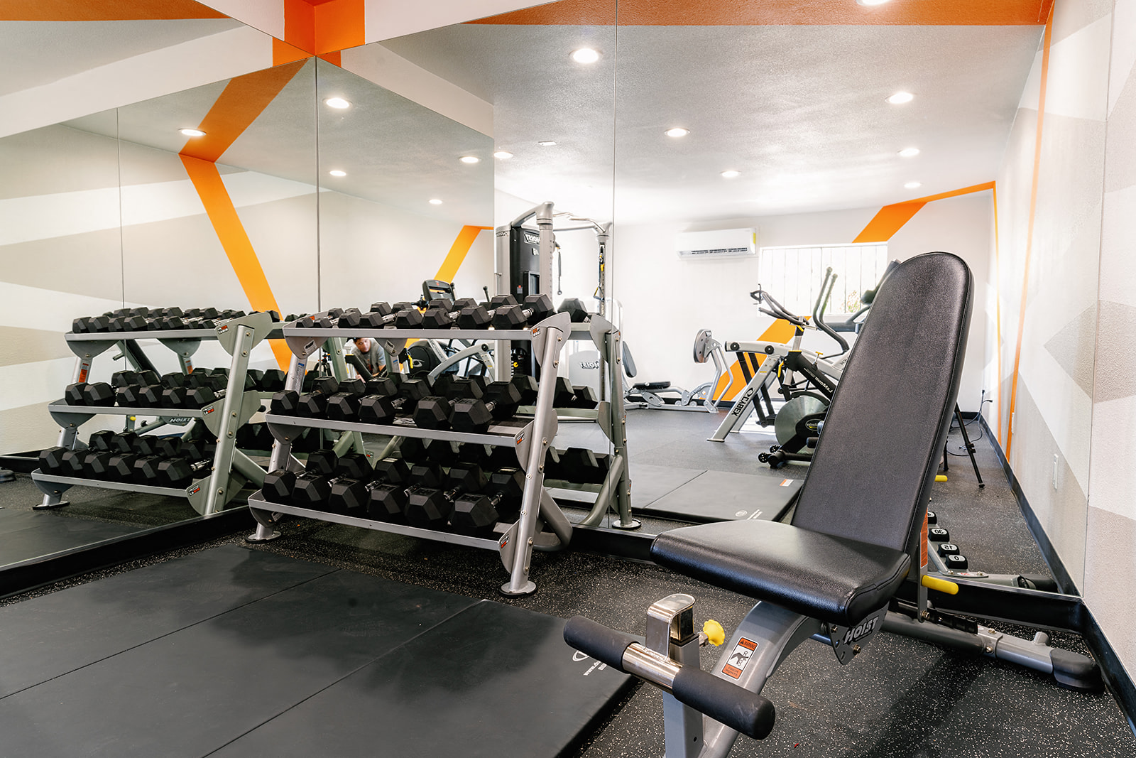 a gym with weights and a chair in the corner of a room