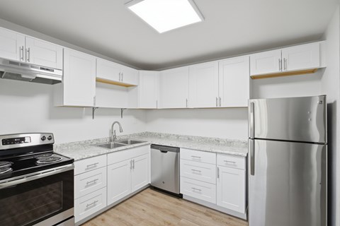 A kitchen with white cabinets and a stainless steel refrigerator.