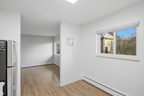 A white room with a window and a refrigerator.