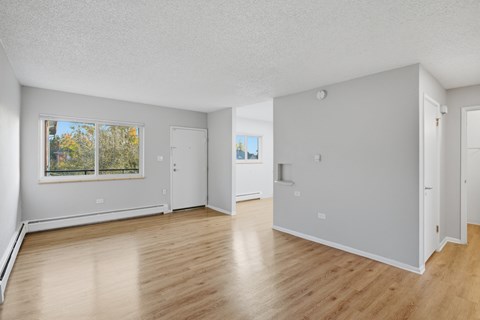 A spacious room with wooden floors and white walls.