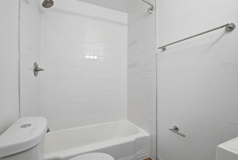 A white bathroom with a toilet, sink, and bathtub.