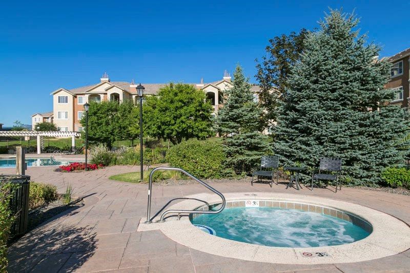 a hot tub in a pool with trees and a building