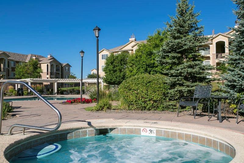 a swimming pool with a hot tub and a building in the background