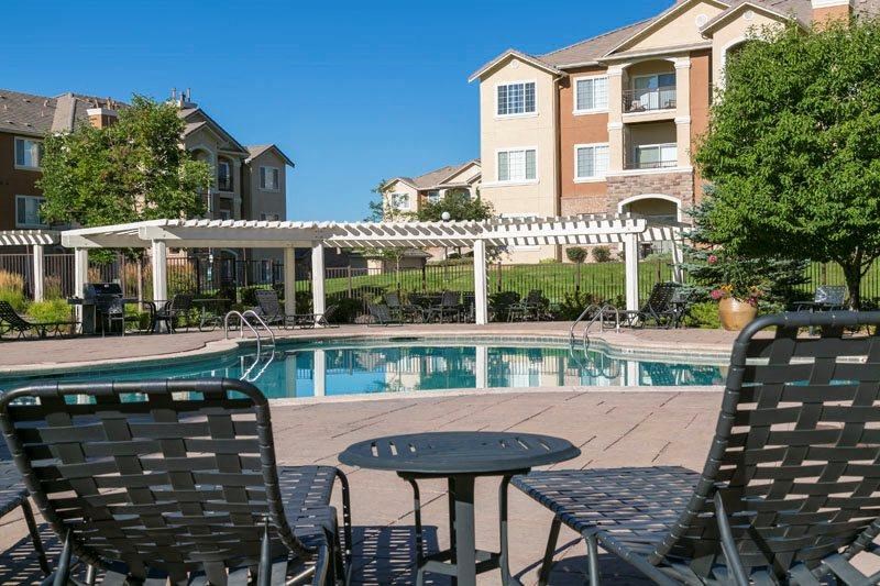 a swimming pool with chairs and tables in front of a building