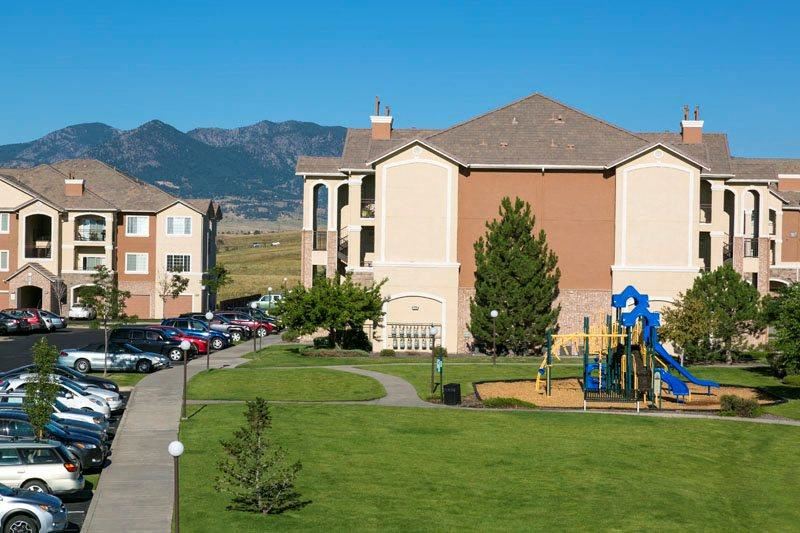 an apartment building with a playground and cars parked