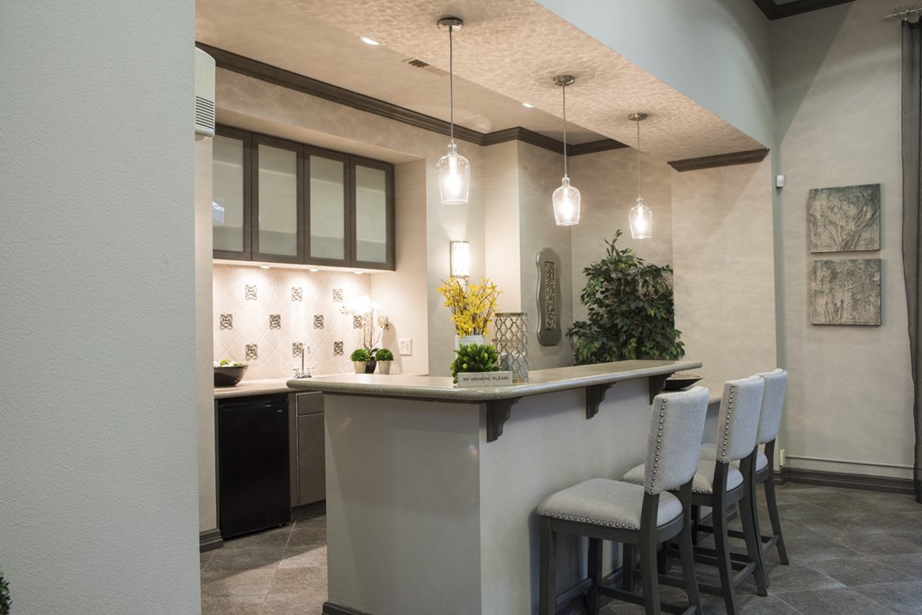 a kitchen with a bar and chairs and lights