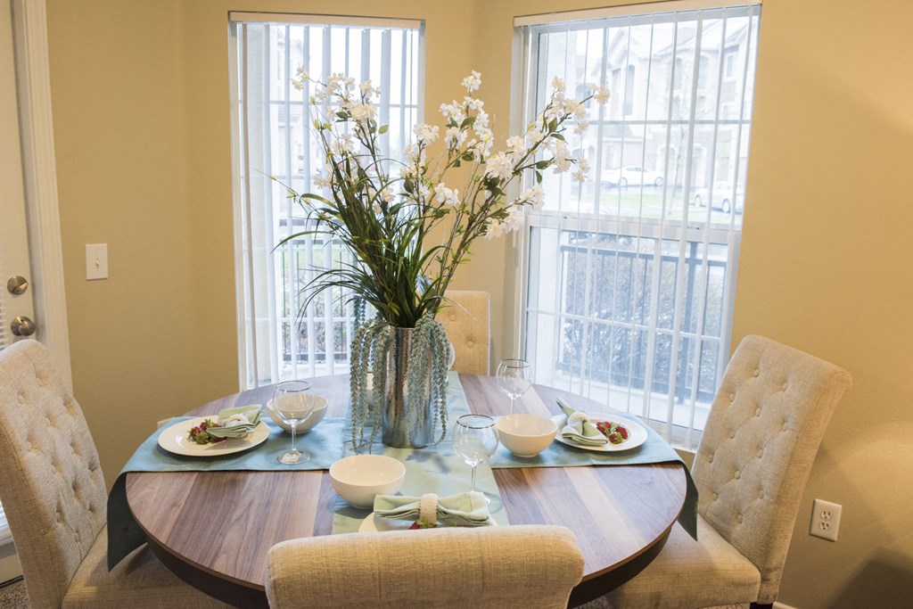 a dining room with a table and chairs and a vase with flowers