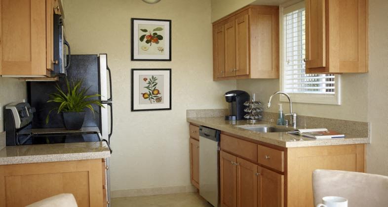 A kitchen with wooden cabinets and a black fridge.