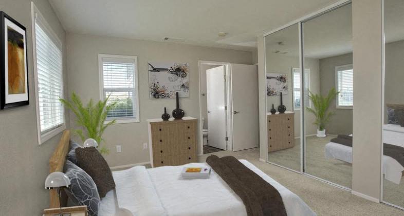 A bedroom with a large bed and a mirrored closet door.