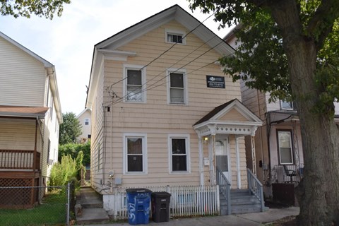 A two-story house with a front porch and a sign on the front.