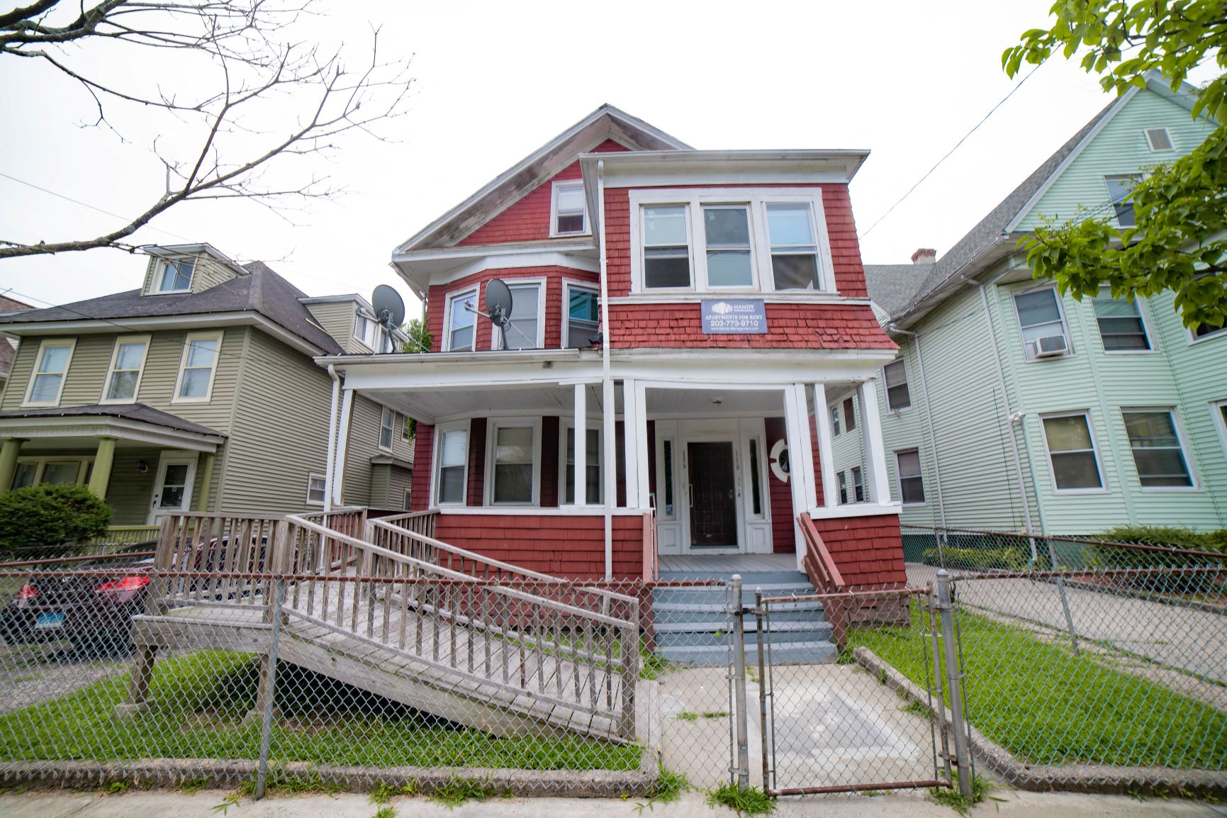 A red and white two story house with a porch and a fence.