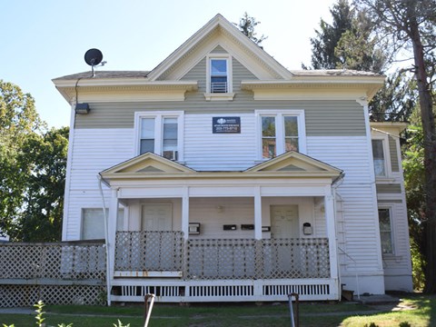A white house with a yellow roof and a balcony.