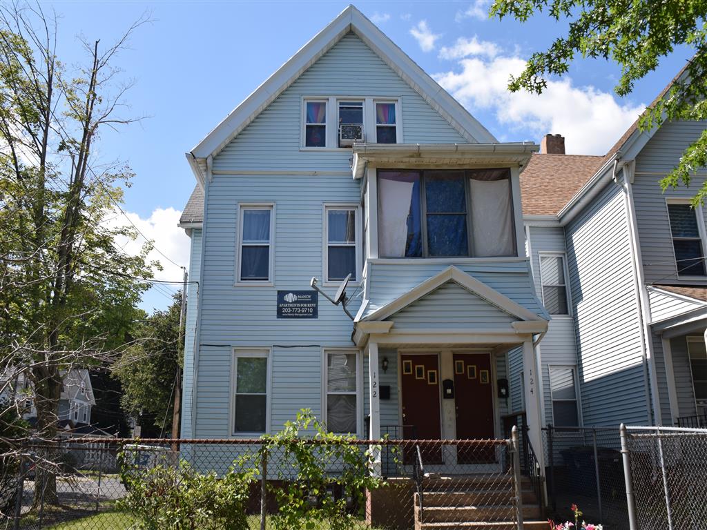 A blue house with a red door and a sign on the front.