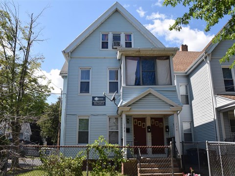 A blue house with a red door and a sign on the front.