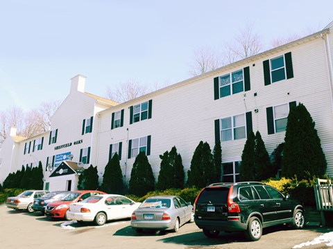 A white building with a sign that says "Skippers Ales" in front of a parking lot.