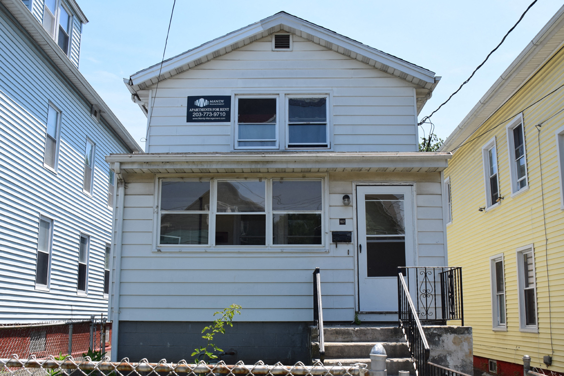 A two-story house with a white exterior and a black door.