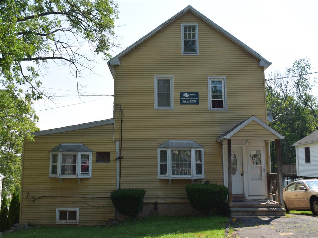 A yellow house with a white door and windows.