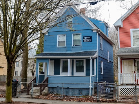 A blue house with a white door and a sign on the front.