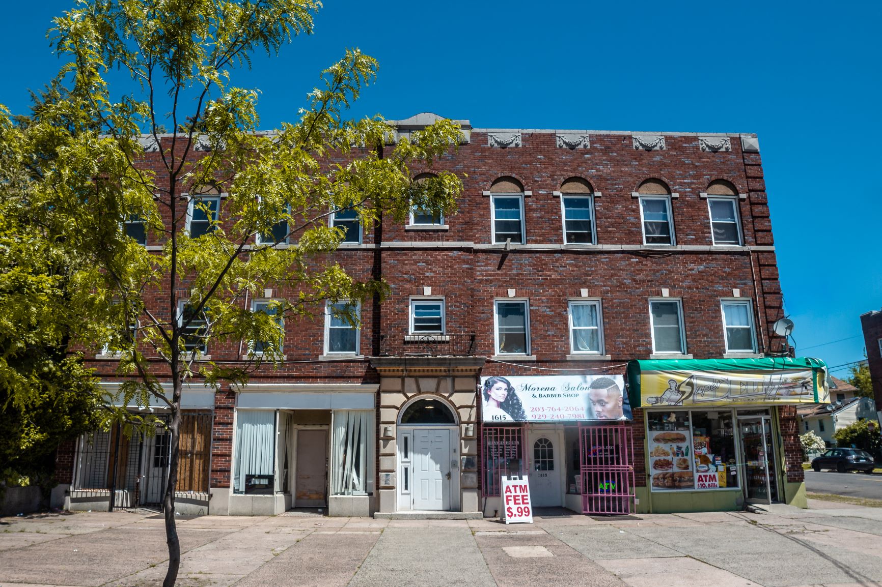 A red brick building with a white awning and a sign that says "ATM".