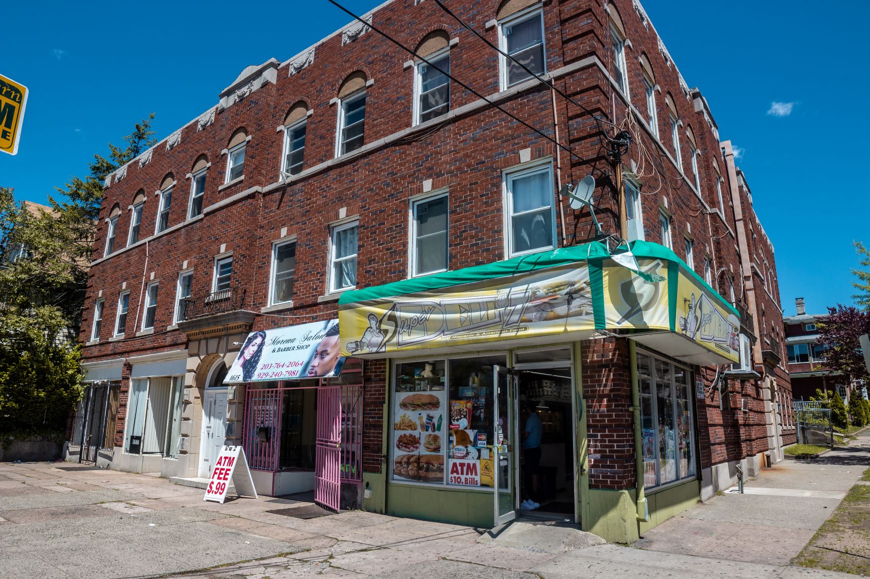A red brick building with a green awning and a sign that says "ATM".