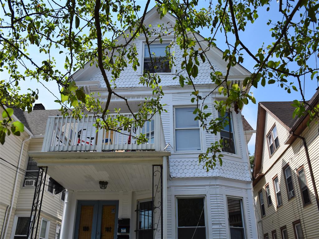 A white house with a balcony and a blue door.