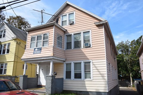 A two-story house with a red car parked in front.