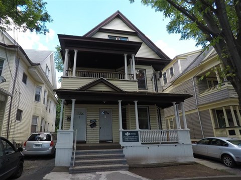 A two-story house with a porch and a sign on the front door.