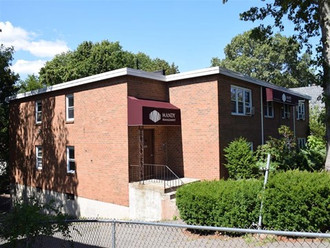 A red brick building with a sign that says MANDI in front of it.