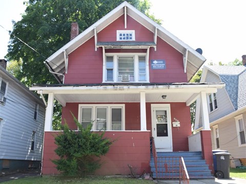 A red house with a white door and a sign on the front.