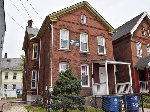 A red brick house with a white door and windows.