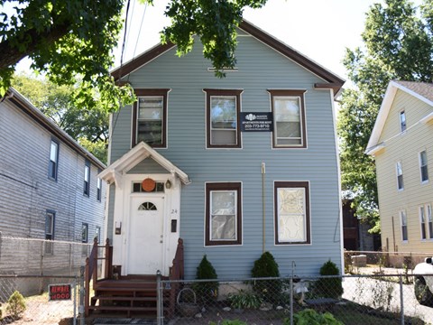 A blue house with a white door and a sign on the front.