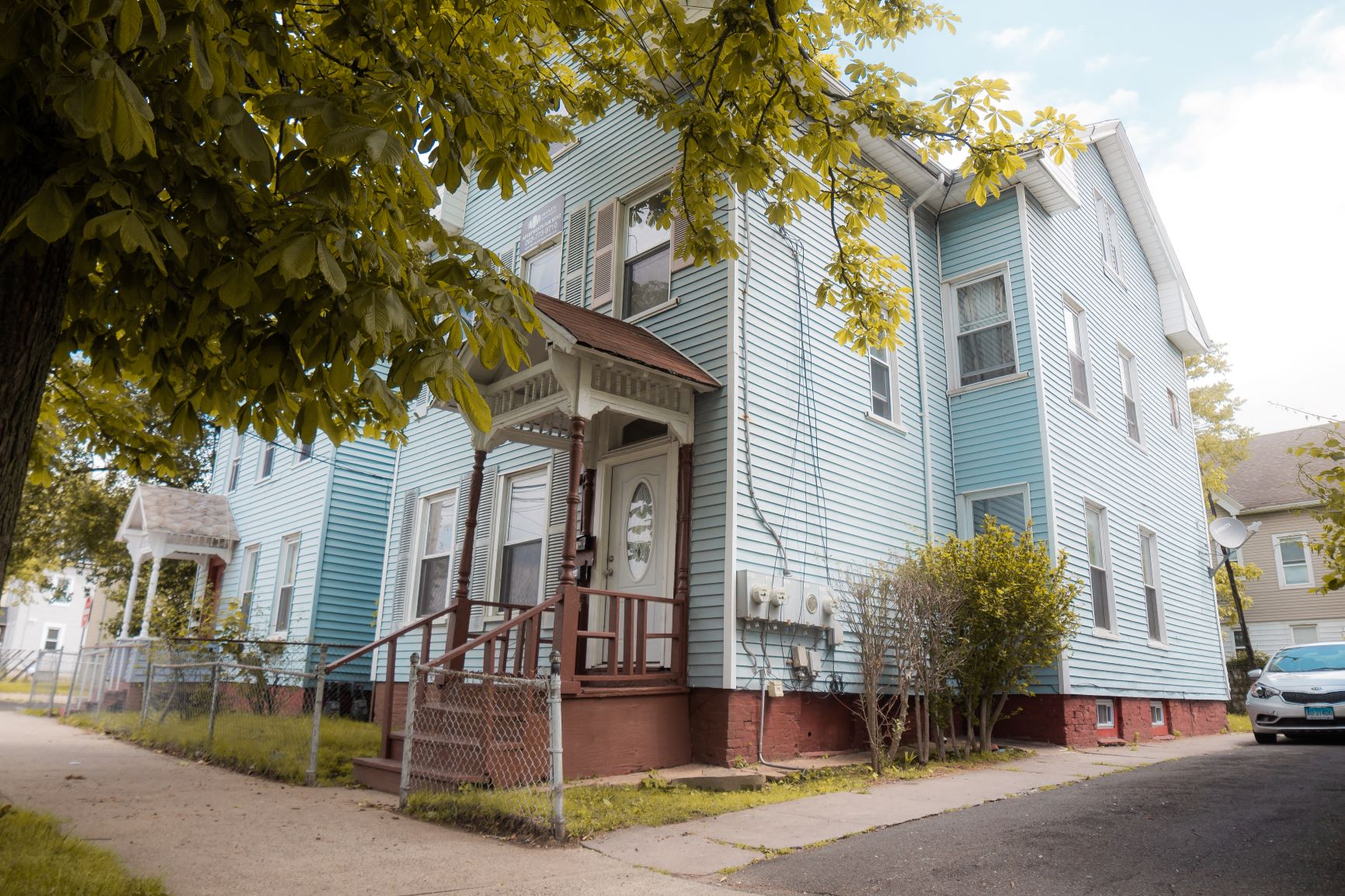 A blue house with a tree in front.