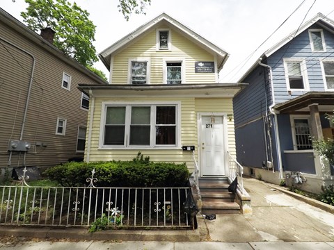A yellow house with a white door and a small porch.