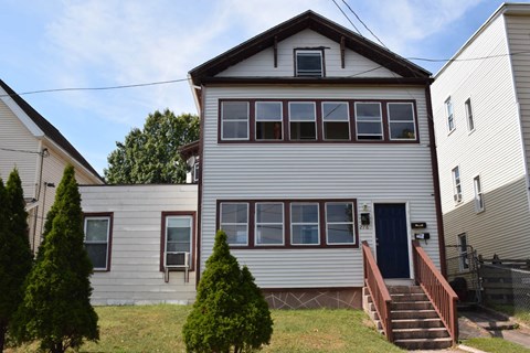 A two-story house with a blue door and a staircase leading to the entrance.