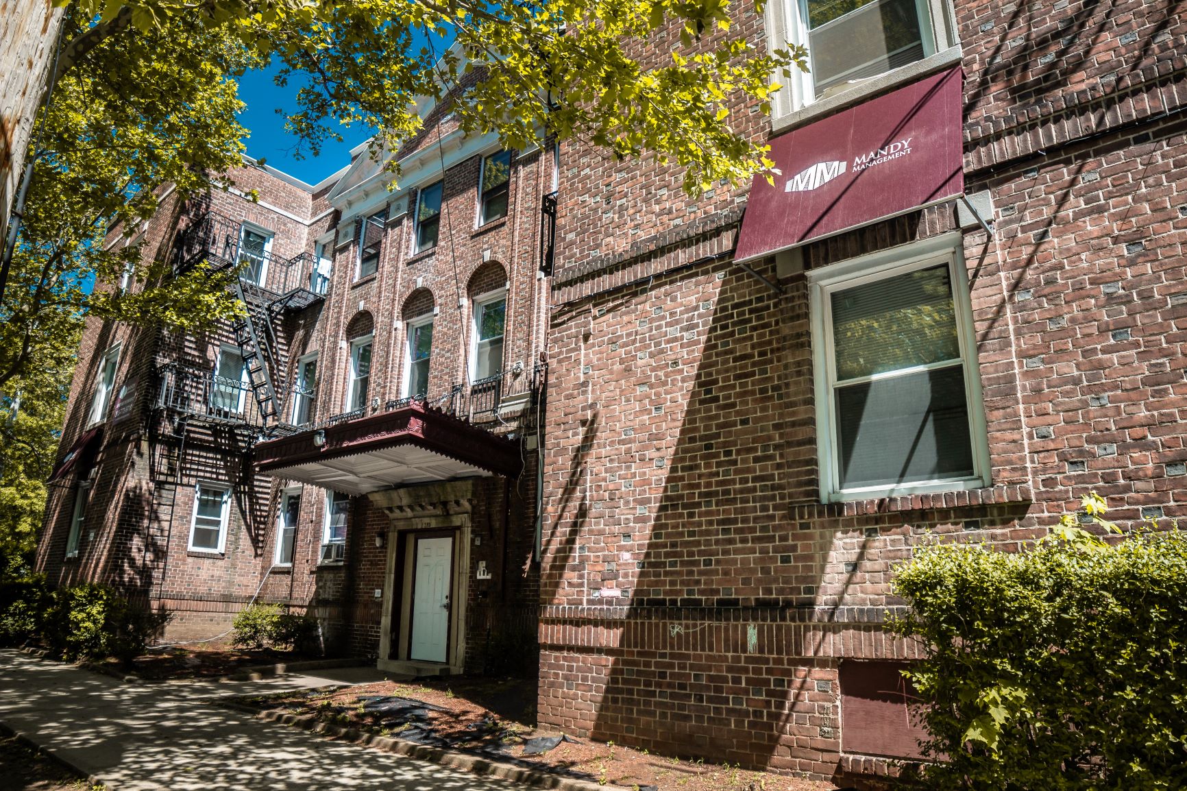 A building with a red awning and a tree in front.