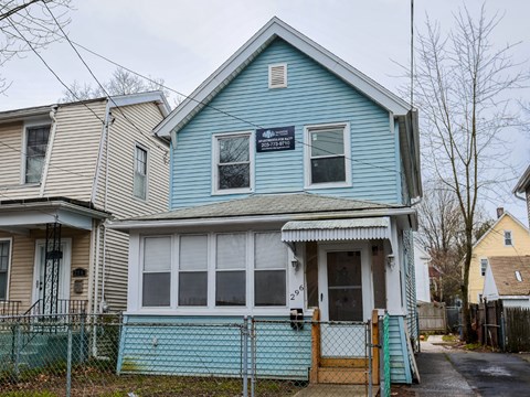 A blue house with a sign on the front window.