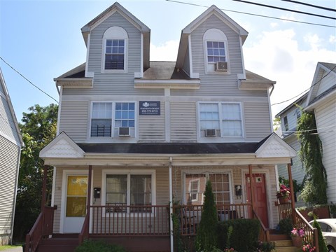 A two-story house with a red door and a balcony.