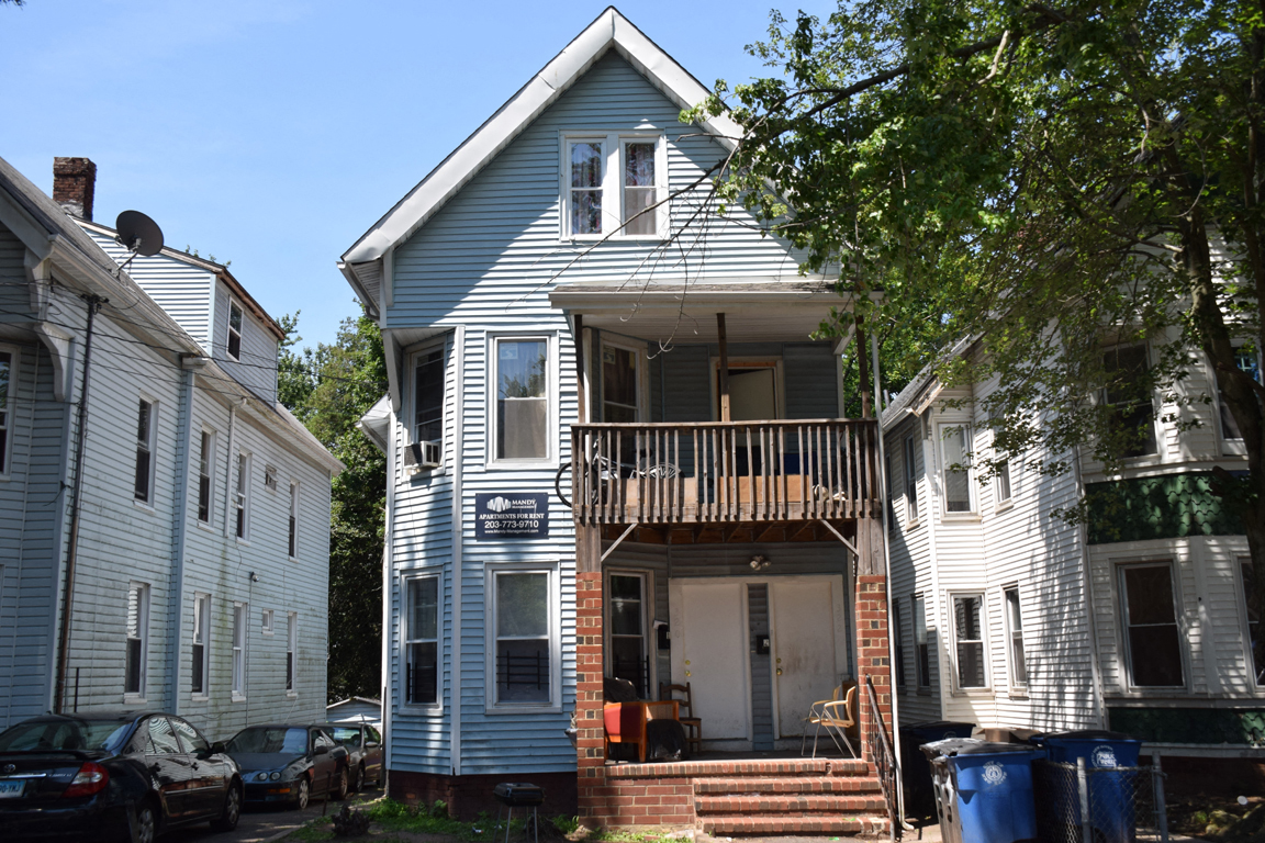 A blue house with a porch and a sign on the front.