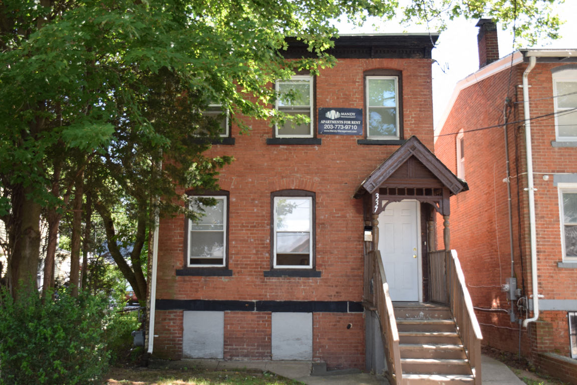 A red brick house with a white door and a sign on the window.