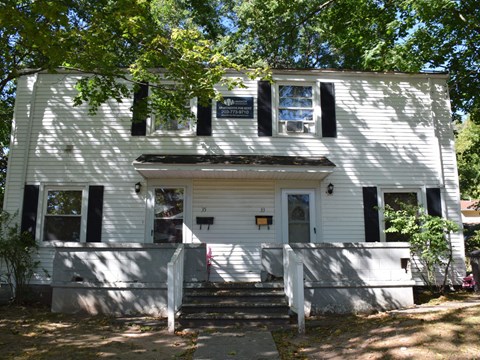 A white house with black shutters and a porch.