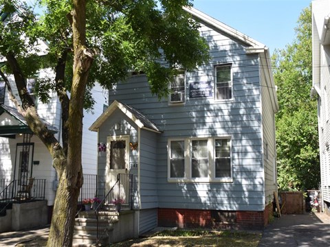 A small blue house with a tree in front.