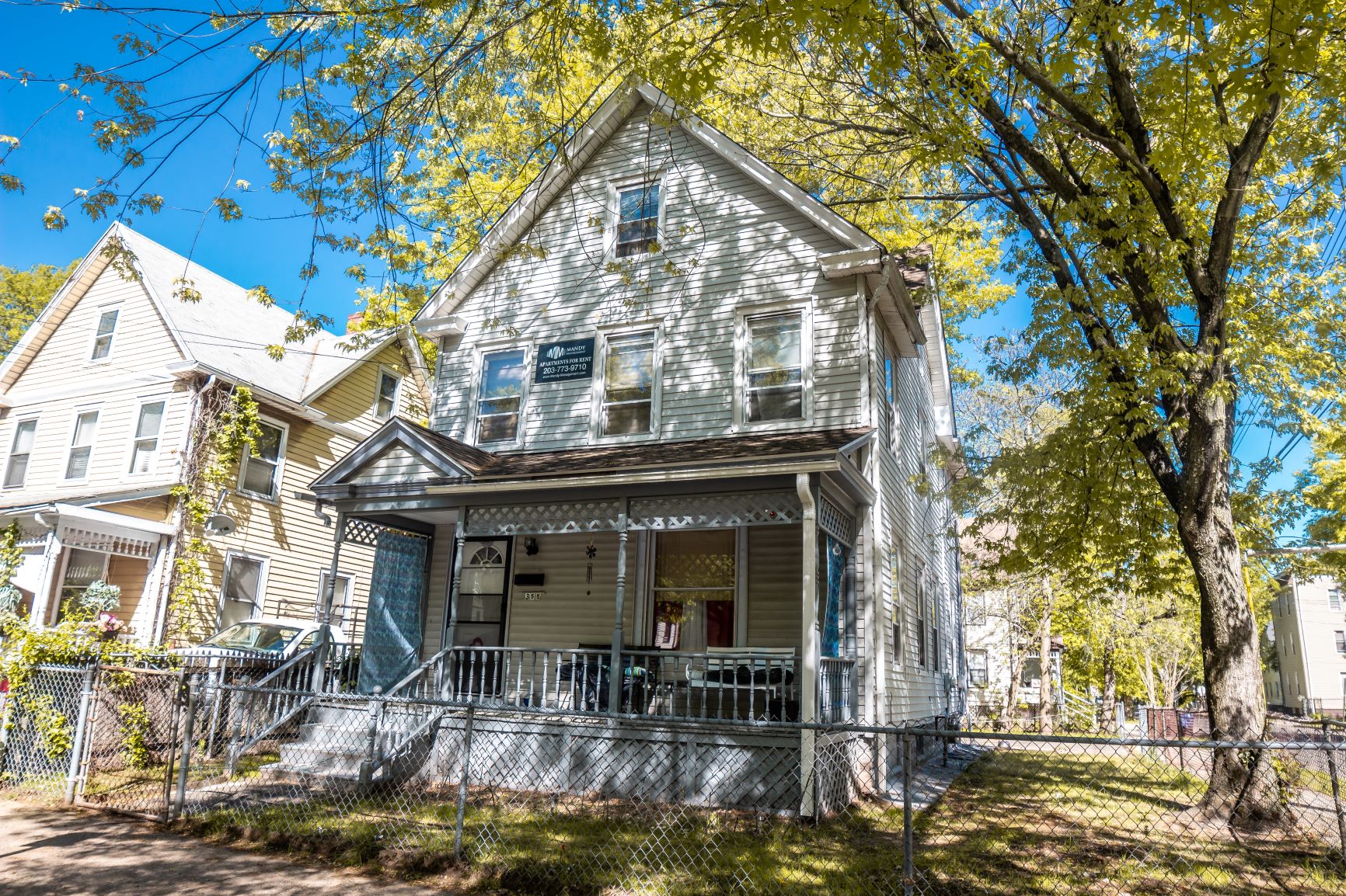 A house with a porch and a tree in front of it.