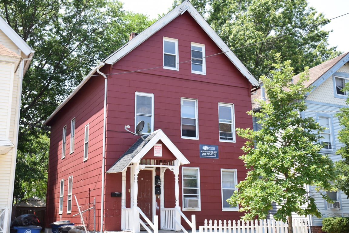 A red house with a white picket fence in front.