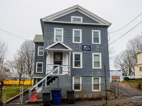 A grey two story house with a sign on the front.