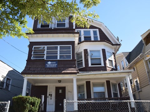 A brown and white two story house with a white fence in front.